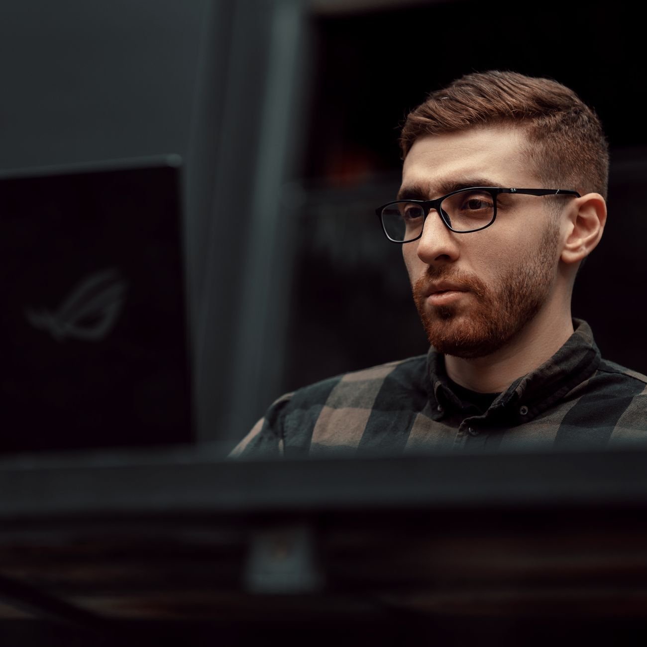 Portrait of a serious man with glasses working on a laptop indoors, showcasing concentration and focus.